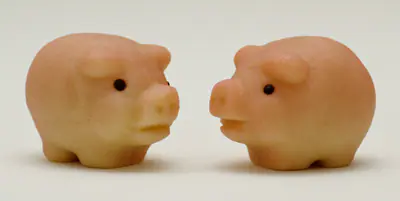 Kaksi vaaleanpunaista marsipaanipossua vastakkain vaalealla taustalla