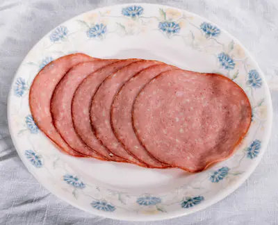 Ohuita meetvurstiviipaleita limittäin kukkareunuksisella lautasella vaalealla liinalla