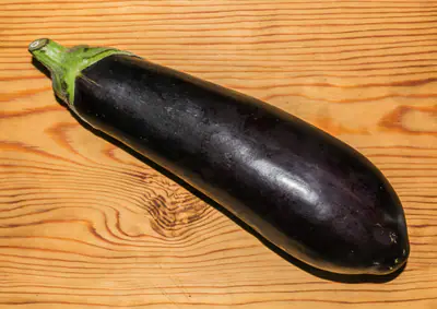 Kokonainen tummanvioletti munakoiso vaalealla puupöydällä