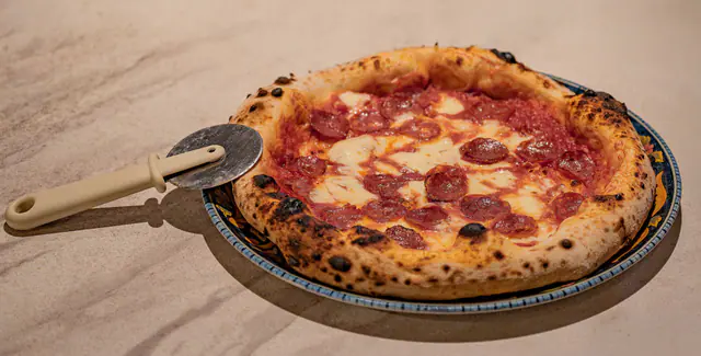 Kokonainen napolilainen salamipizza, jossa paahtuneet reunat, sulaa mozzarellaa ja tomaattikastiketta