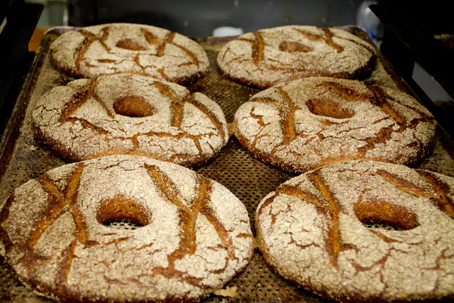 Kuusi jauhopintaista ruisreikäleipää rei'itetyllä leivinpellillä