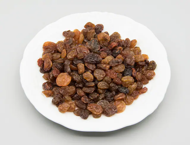 Rusinoita valkoisella lautasella vaaleanharmaalla taustalla